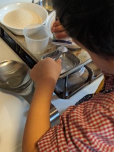 Child helping to measure ingredients in the kitchen