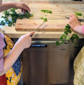 Children helping to cut greens on a cutting board