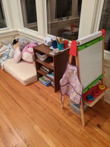 A child's easel and apron in a playroom