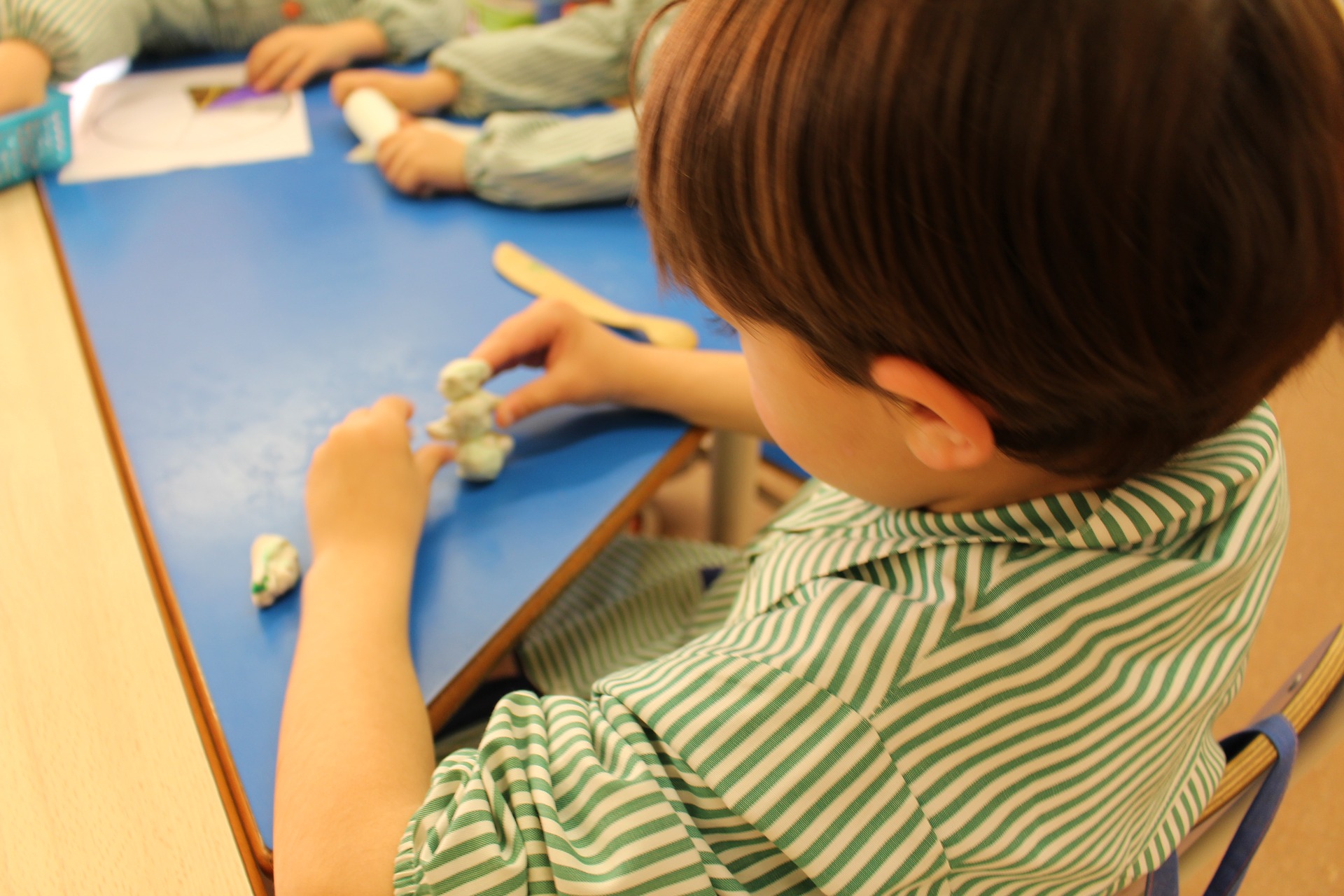 Child playing with clay at a blue table