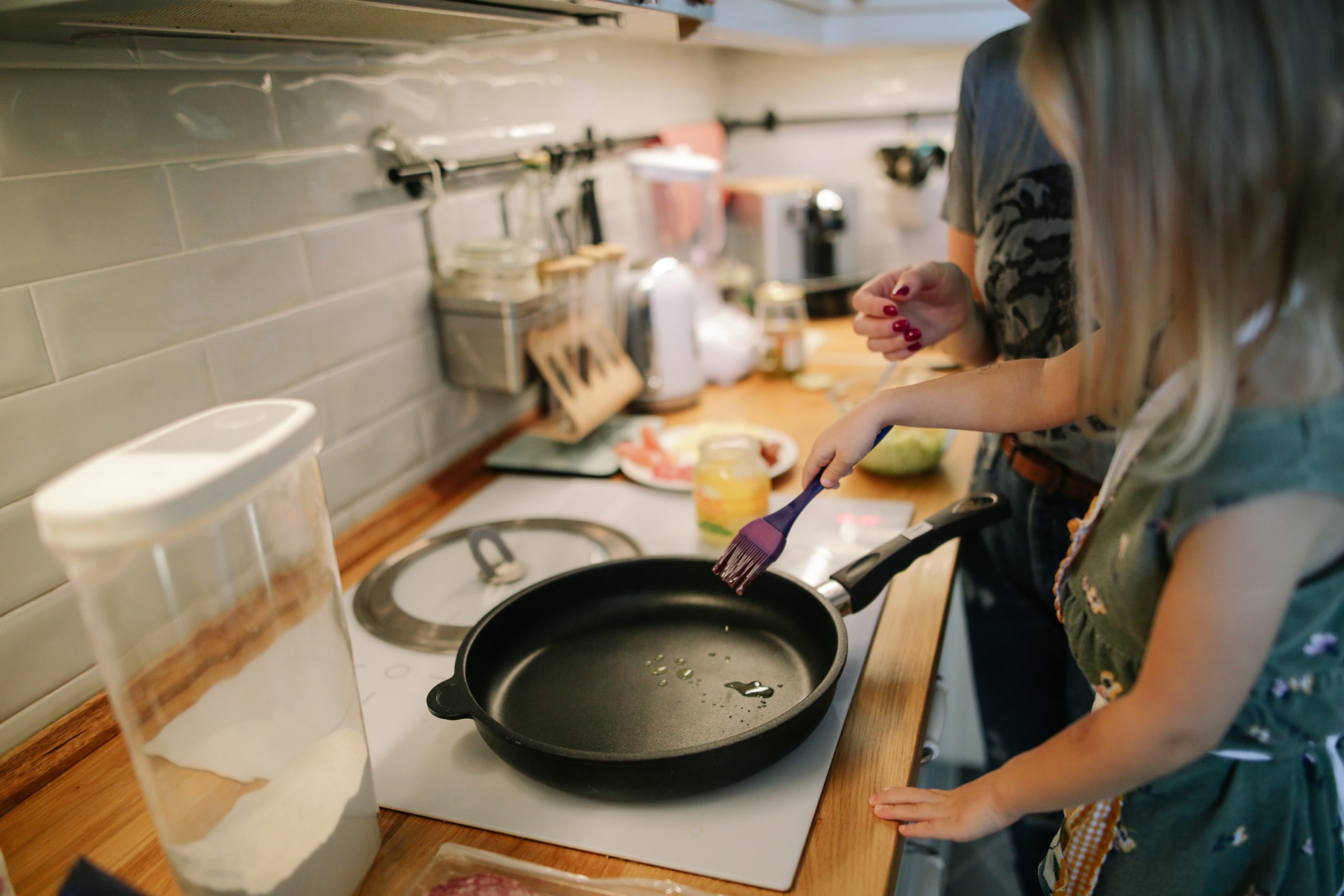 A child holding a brush over a pan in a kitchen