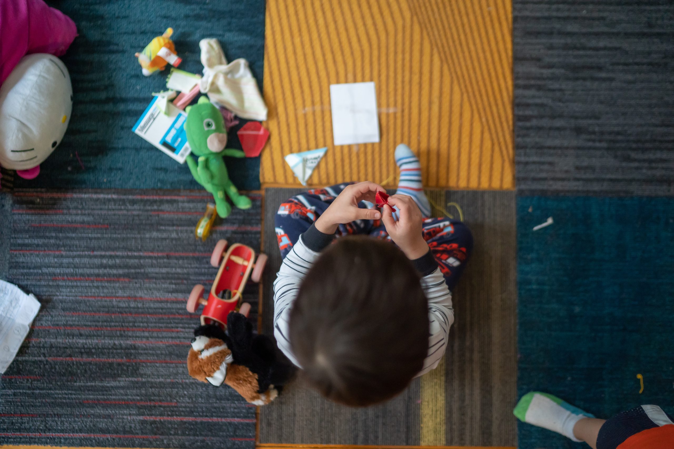 Toddler playing with toys on multi-colored carpeting